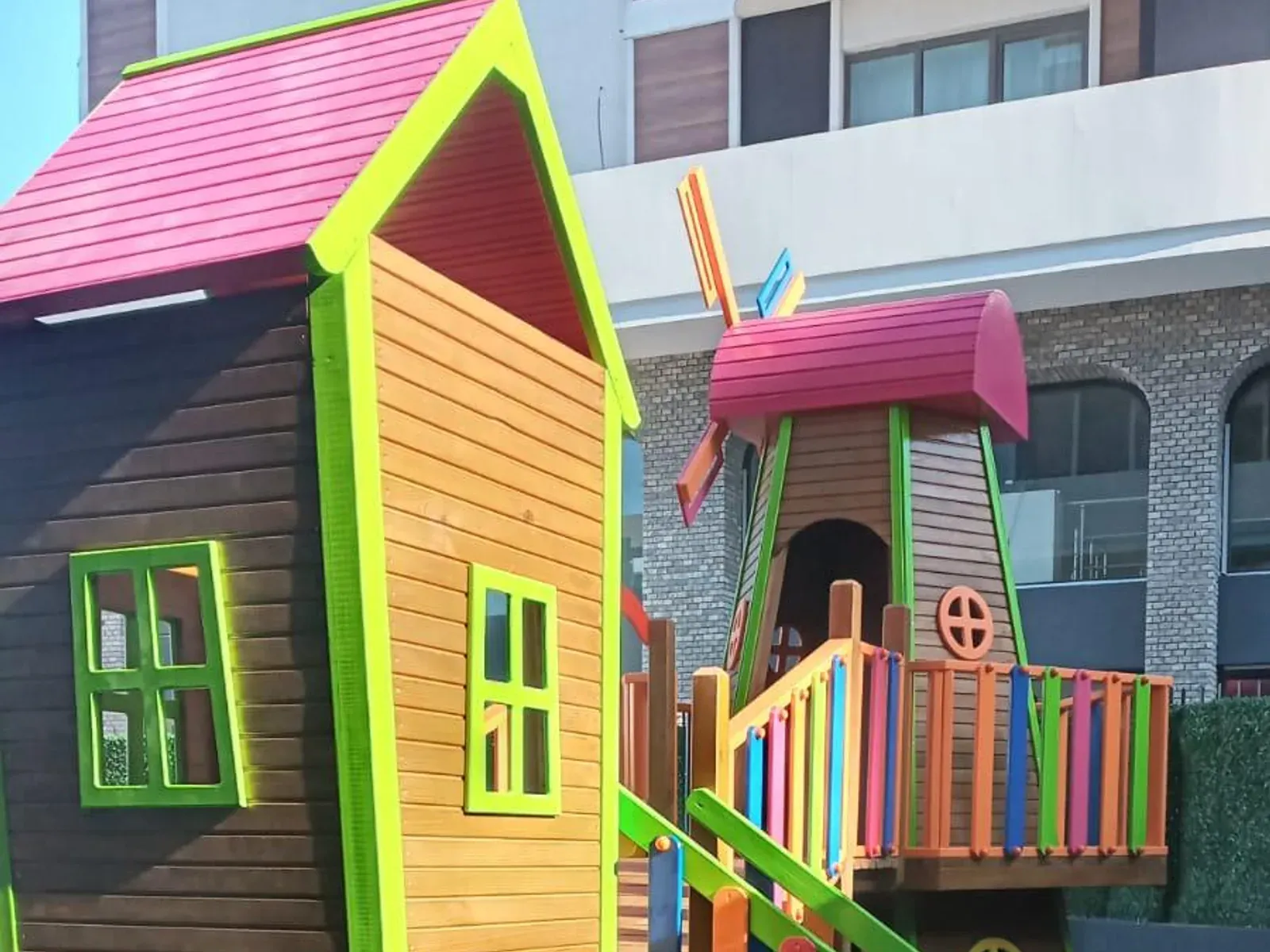 Renkli boyalı ahşap oyun evi ve platform bağlantılı bahçe oyun grubu